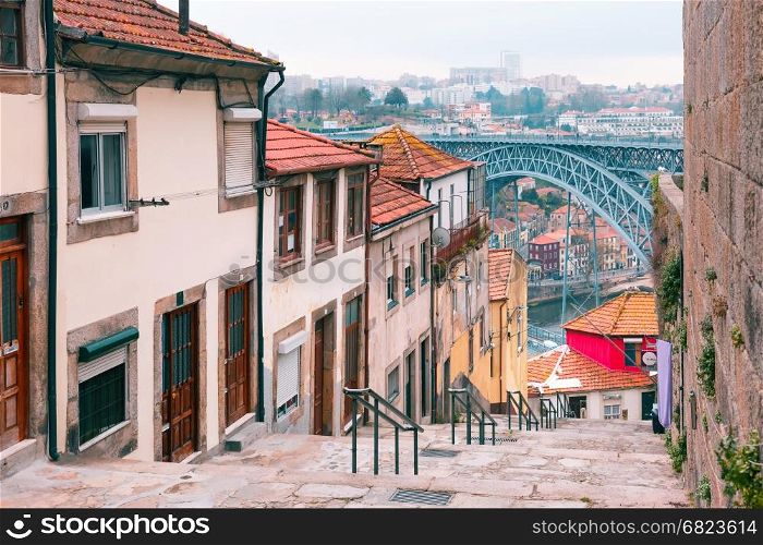 Old houses and stairs in Ribeira, Porto, Portugal. Traditional old houses in Ribeira and stairs down to the river Douro, Dom Luis I or Luiz I iron bridge on the background, Porto, Portugal