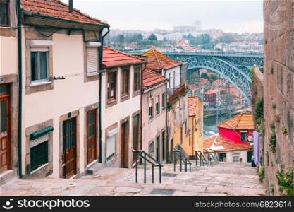 Old houses and stairs in Ribeira, Porto, Portugal. Traditional old houses in Ribeira and stairs down to the river Douro, Dom Luis I or Luiz I iron bridge on the background, Porto, Portugal