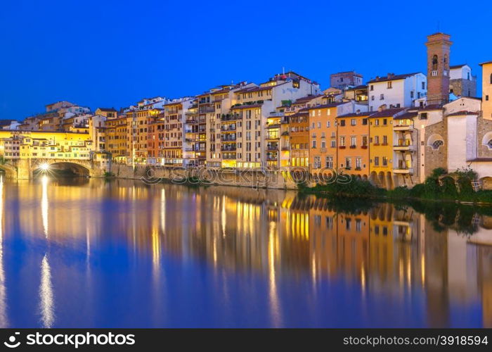 Old houses and tower on the embankment of the River Arno and Ponte Vecchio at night, Florence, Tuscany, Italy