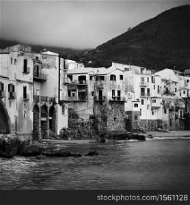 Old houses by the sea in Cefalu in Sicily, Italy. Black and white photography
