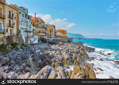 Old houses on rocky coast in Cefalu town, Sicily, Italy
