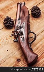 Old hunting musket on a light wooden background with forest cones. Old musket 