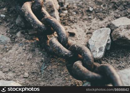 Old iron chain with rusty links on stones