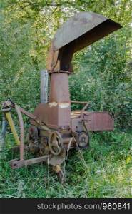 Old iron combine harvester in front of trees