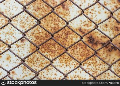 Old iron mesh against a white rusty metal surface with spots and corrosion.