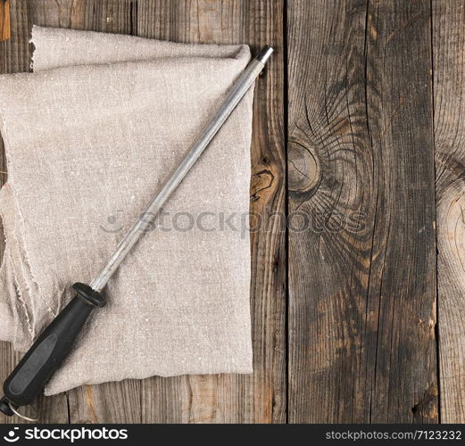 old iron sharpener with handle for kitchen knives on gray wooden background, top view, copy space