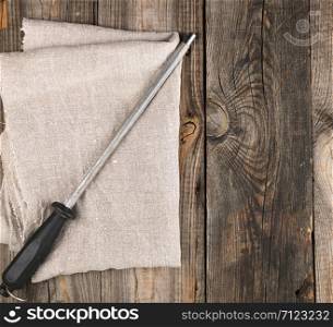 old iron sharpener with handle for kitchen knives on gray wooden background, top view, copy space