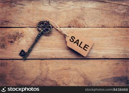 Old key with tag and text sale on wooden