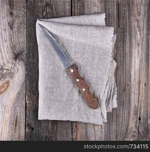 old kitchen knife on a gray napkin, gray wooden background