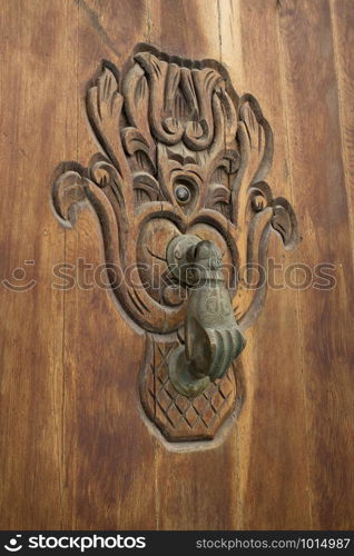 Old knocker in the shape of a hand on a wooden door in Asilah, Morocco