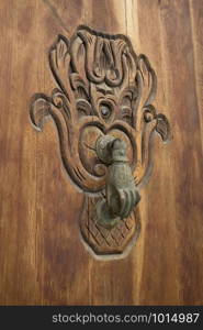 Old knocker in the shape of a hand on a wooden door in Asilah, Morocco