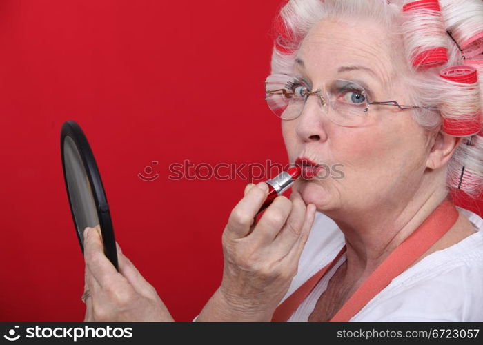 Old lady applying lipstick