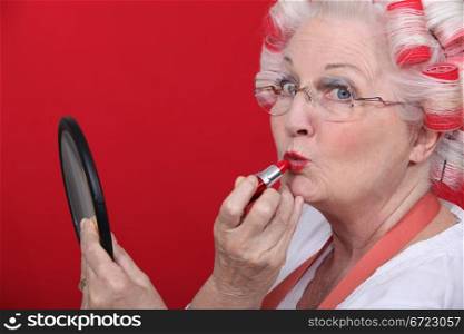 Old lady applying lipstick