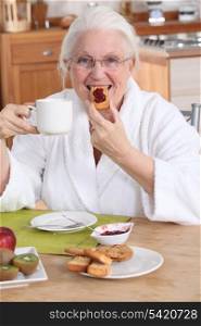 Old lady having breakfast in kitchen