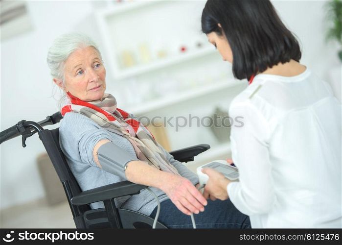 Old lady in a wheelchair having her blood pressure taken