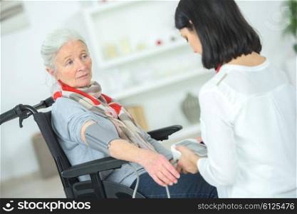 Old lady in a wheelchair having her blood pressure taken