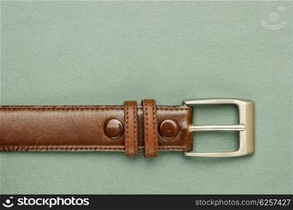 Old leather belt with a buckle on a green background