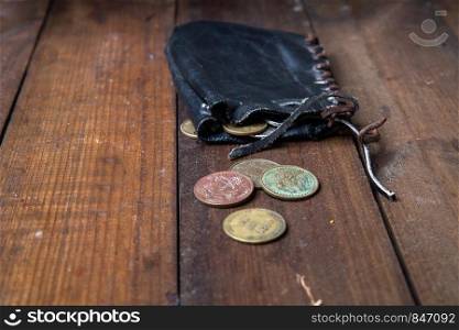 Old leather pirate wallet - a bag with small copper coins lying on a dark wooden surface. old pirate purse