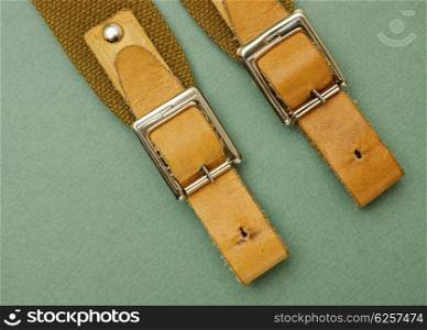 Old leather strap with a buckle on a green background