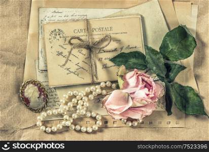 Old letters, postcards and vintage accessories. Paper background with dry rose flower. Retro style toned picture