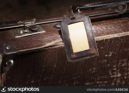 Old luggage tag on an old brown suitcase.