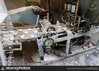 Old machine for forming dough pieces on a conveyor belt for the production of Arab flatbread in a large bakery in Aqaba, Jordan, middle east