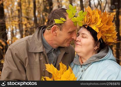 Old man and old woman with wreath of maple leaves face to face