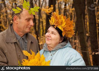 Old man and old woman with wreath of maple leaves look against each other