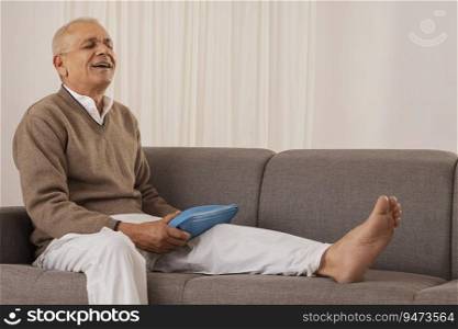 Old man applying hot water bag for relieving from knee joint pain