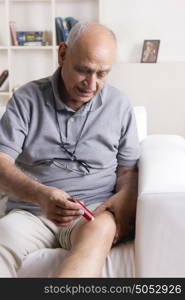 Old man applying ointment on knee
