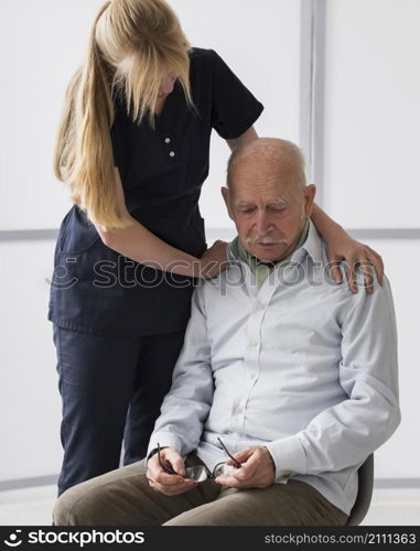 old man crying nursing home with nurse consoling him