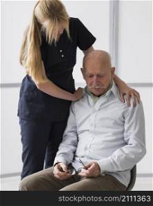 old man crying nursing home with nurse consoling him