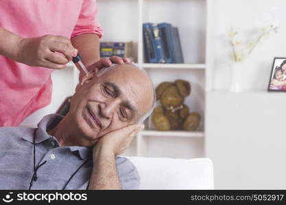 Old man getting ear drops put in