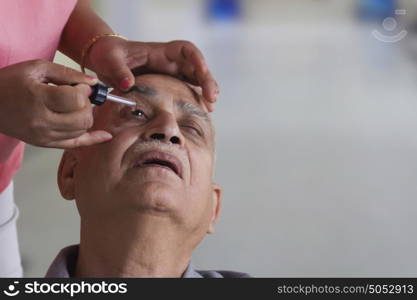 Old man getting eye drops put in