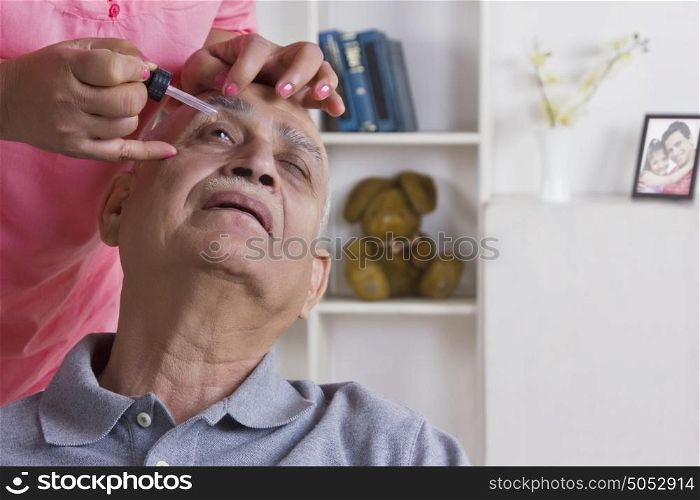 Old man getting eye drops put in