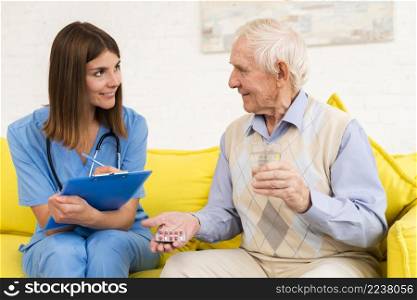 old man holding his pills while talking nurse