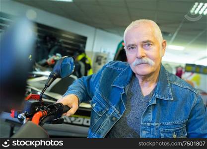 old man posing for picture while sitting on motorbike