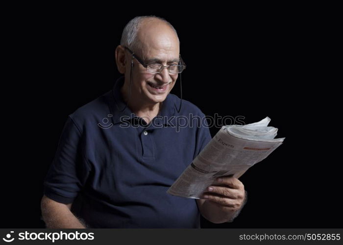 Old man reading newspaper smiling