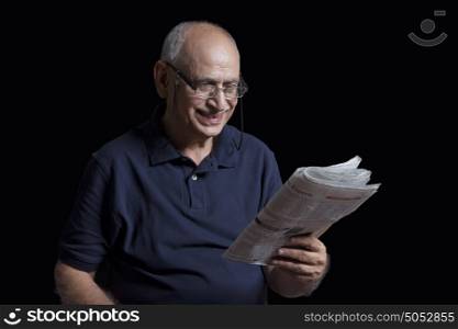 Old man reading newspaper smiling