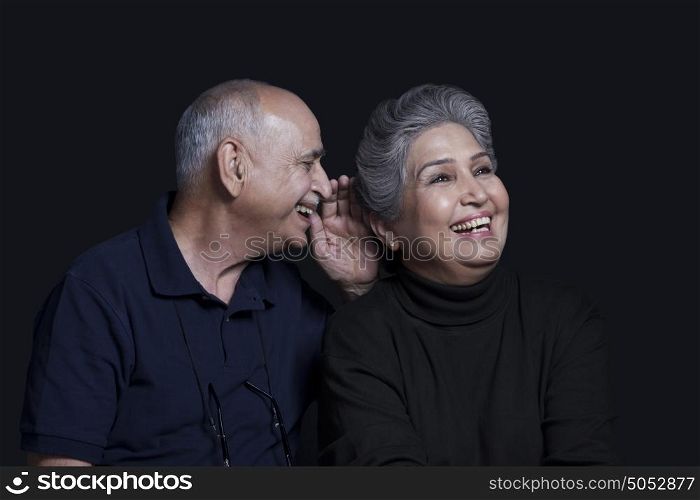 Old man whispering in womans ear