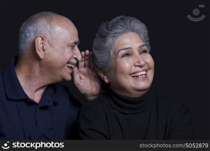 Old man whispering in womans ear