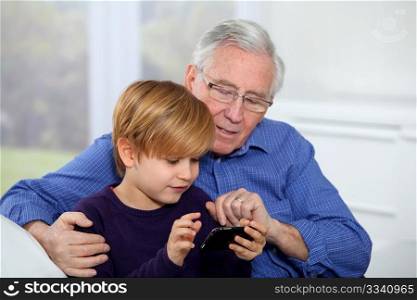 Old man with little boy playing video game on telephone