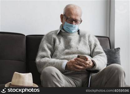 old man with medical mask nursing home using smartphone