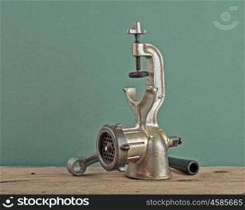 Old manual meat grinder on a wooden table