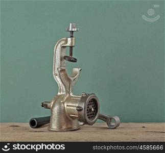 Old manual meat grinder on a wooden table