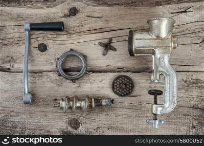 Old manual meat grinder unassembled on a wooden table