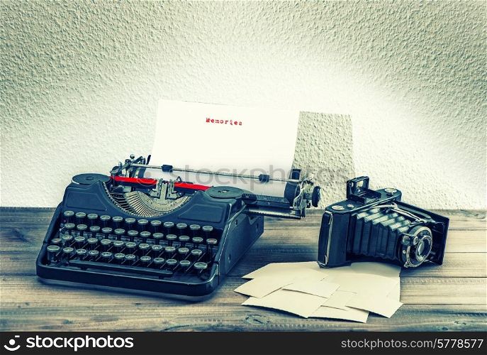 old mechanical typewriter and vintage photo camera on wooden background. antique objects. memories concept