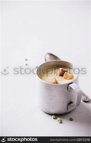 Old metal cup of pea soup on concrete background, close up