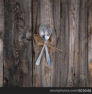 old metal fork and spoon tied with a brown rope on a gray wooden table