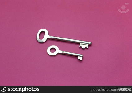 Old metal keys close-up on bright crimson paper background